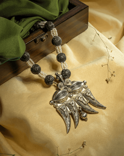 Oxidized 925 sterling silver tribal pendant necklace featuring a 4-claw design strung on black textured lava beads and white pearls.
