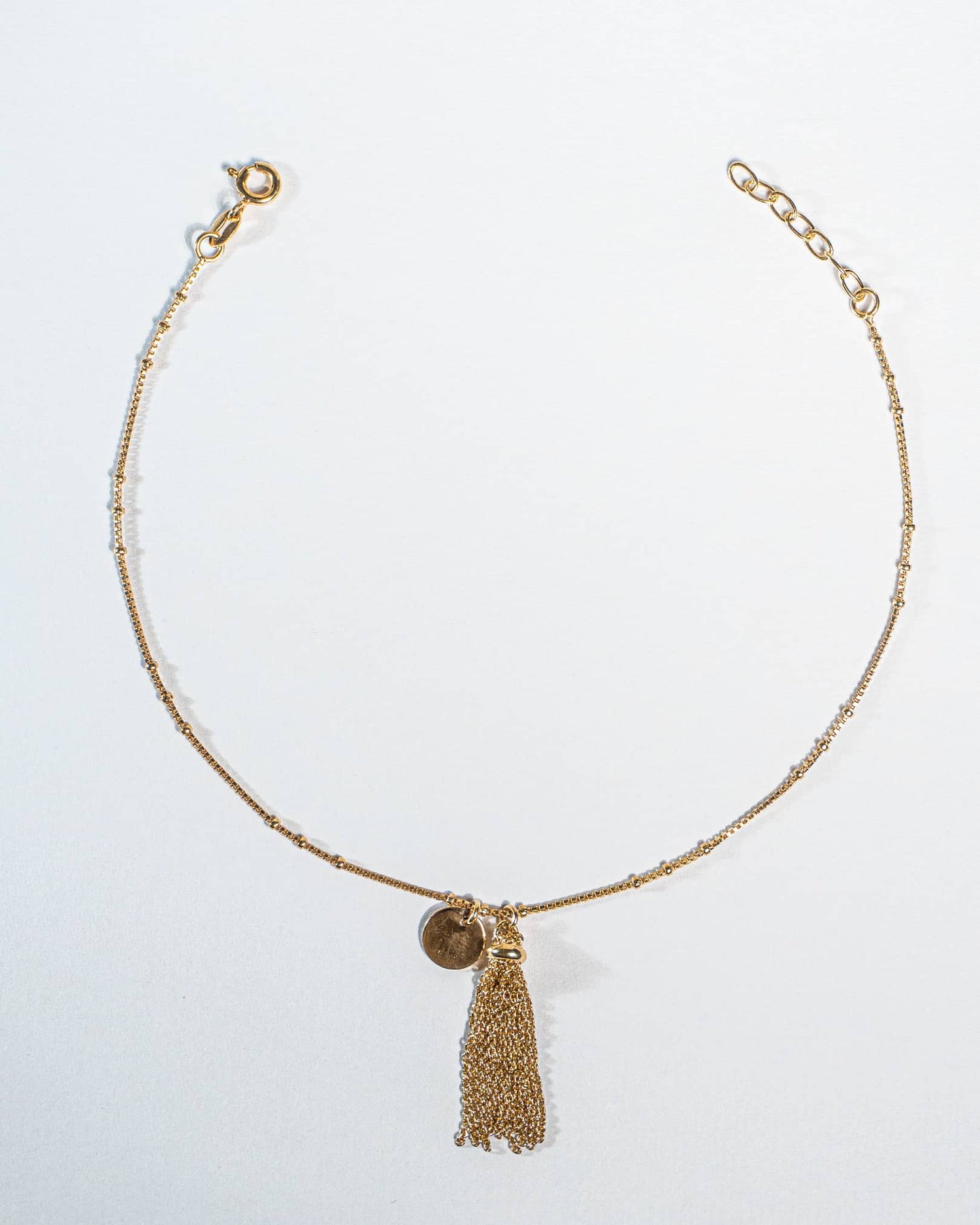 Pair of 18K gold plated sterling silver anklets with tassel on a white background