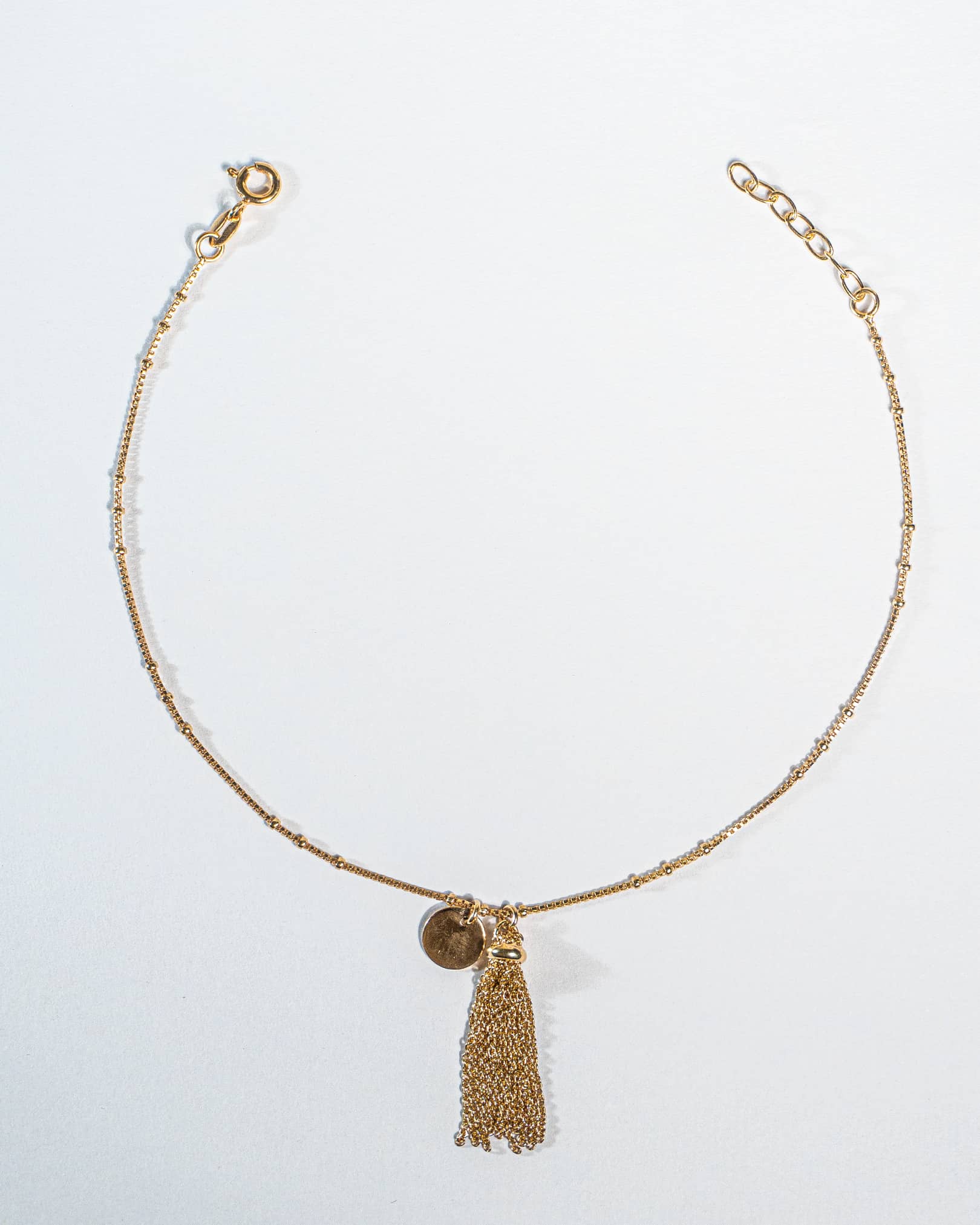 Pair of 18K gold plated sterling silver anklets with tassel on a white background