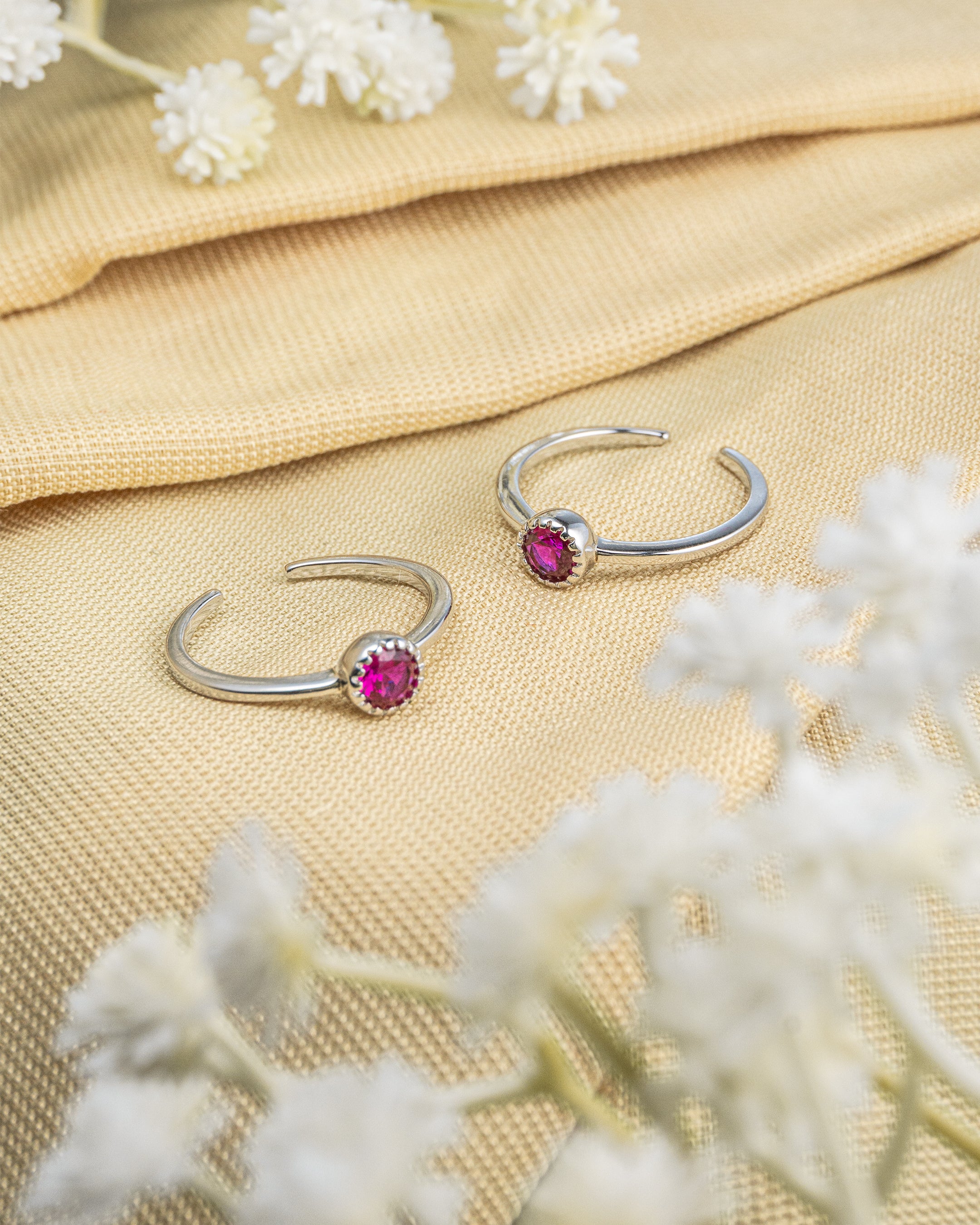 Pair of 92.5 sterling silver adjustable toe rings featuring a single round pink solitaire stone.