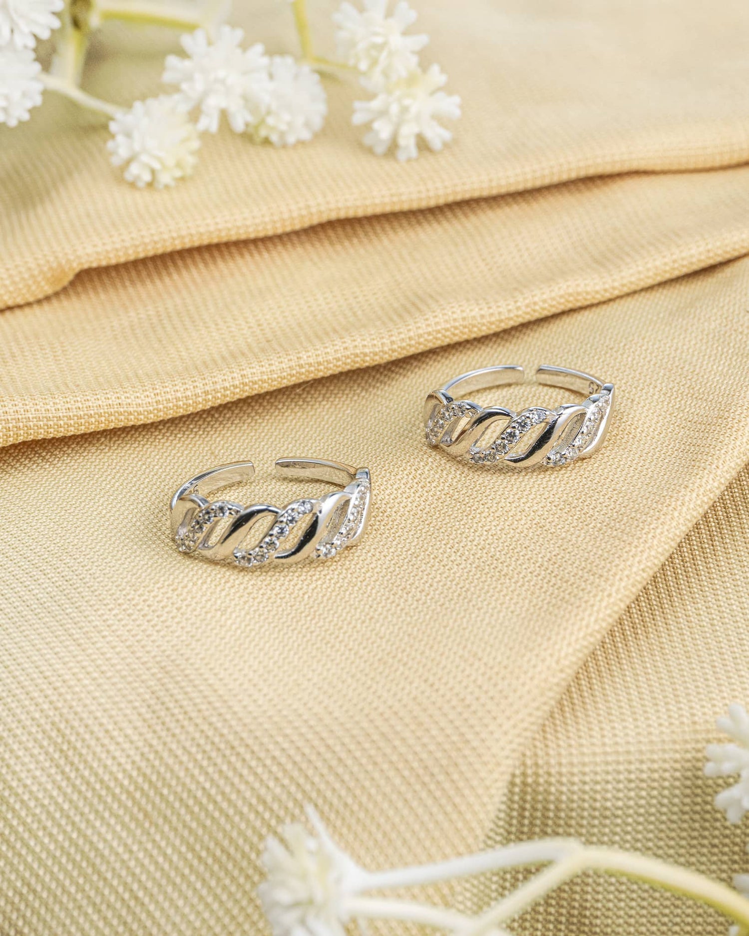 Pair of 92.5 sterling silver band toe rings featuring a white stone twisted wave design.