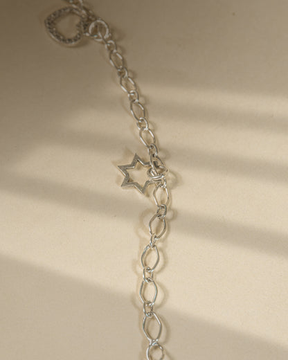 Pair of 925 sterling silver chain anklets featuring dangling heart and star charms on a beige background.