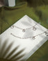 Pair of 925 sterling silver chain anklets featuring dangling heart and star charms on a beige background.