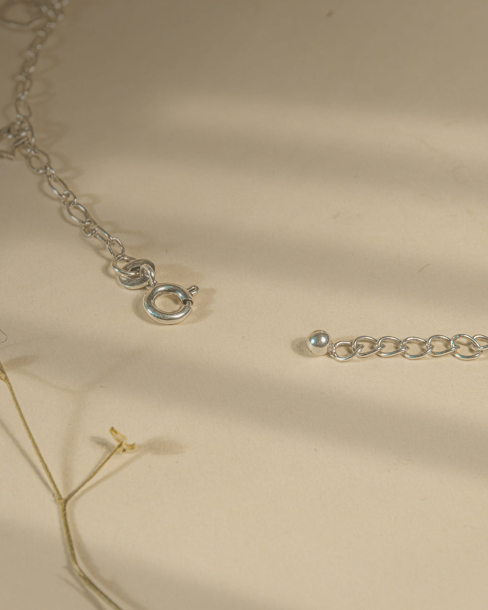 Pair of 925 sterling silver chain anklets featuring dangling heart and star charms on a beige background.