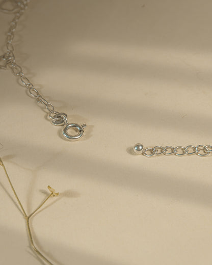 Pair of 925 sterling silver chain anklets featuring dangling heart and star charms on a beige background.