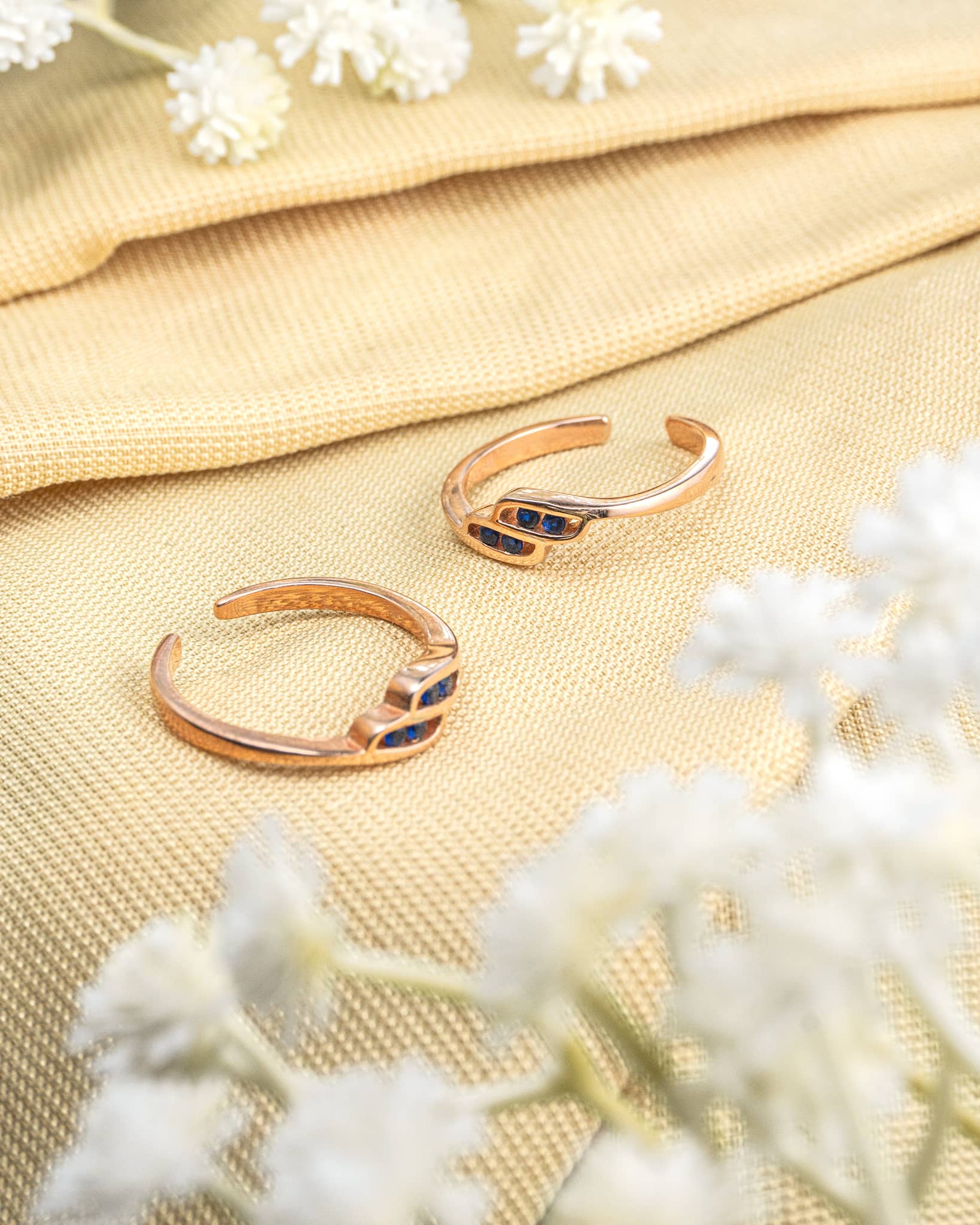 Pair of gold plated 92.5 sterling silver adjustable toe rings featuring blue stones in a wave design.