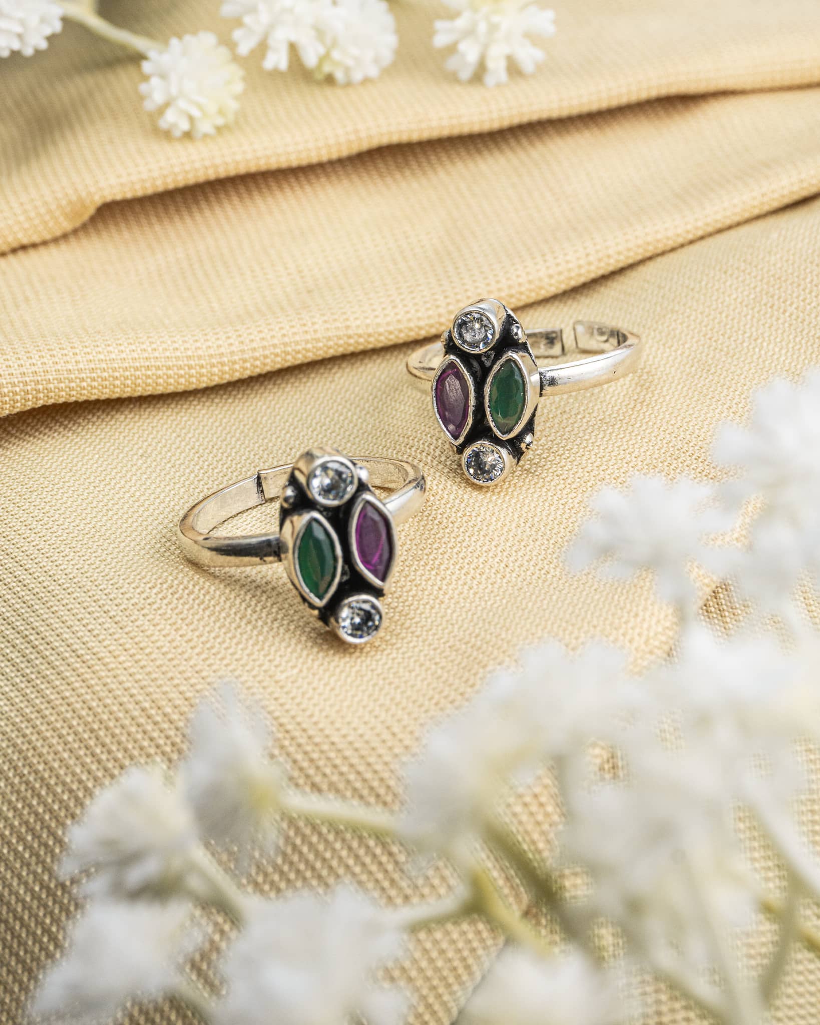 Pair of oxidized 92.5 sterling silver toe rings featuring a 4-stone cluster of green purple and white stones.