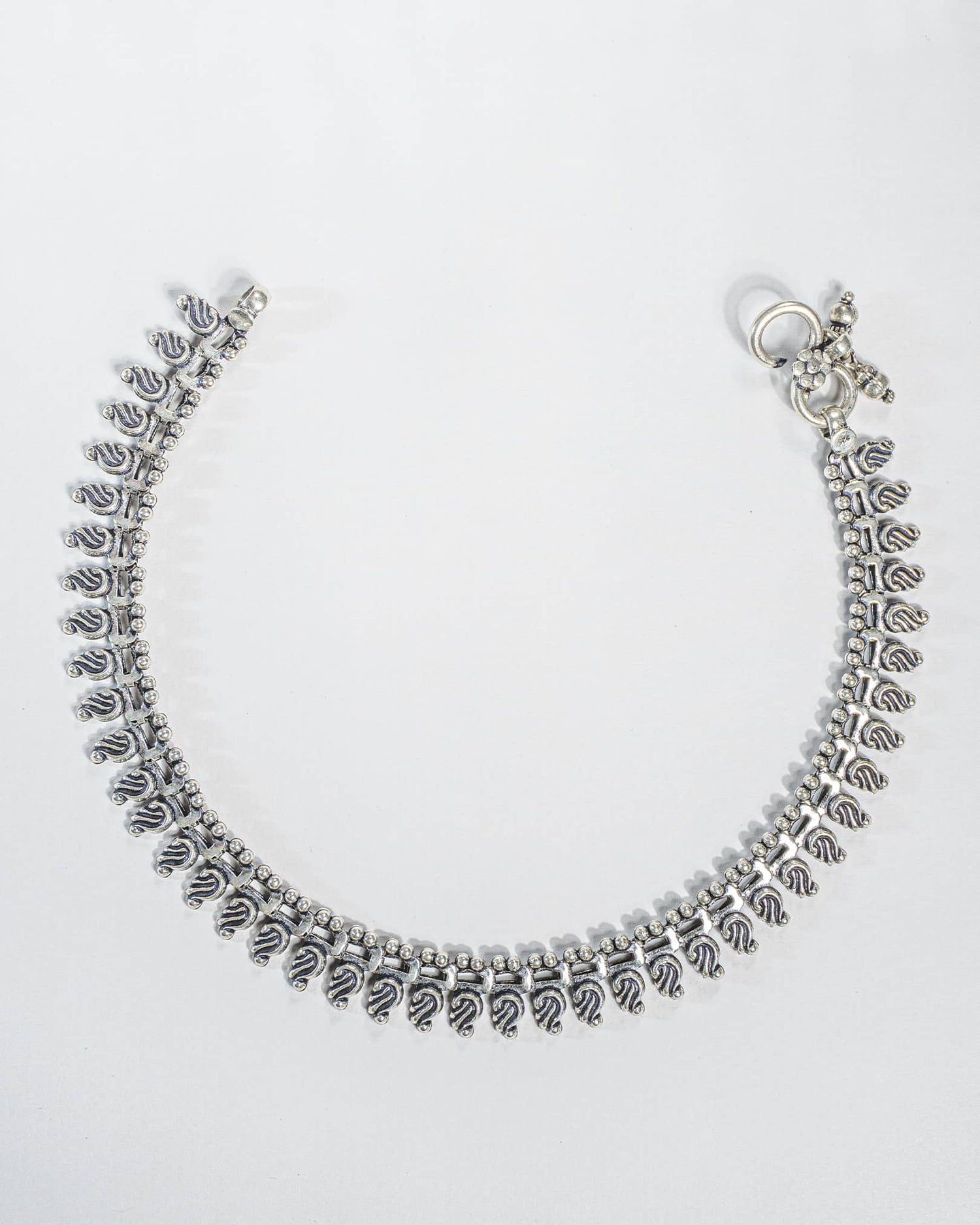 Pair of traditional oxidized silver anklets featuring repeating paisley mango motifs and small silver beads Full details