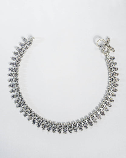Pair of traditional oxidized silver anklets featuring repeating paisley mango motifs and small silver beads Full details