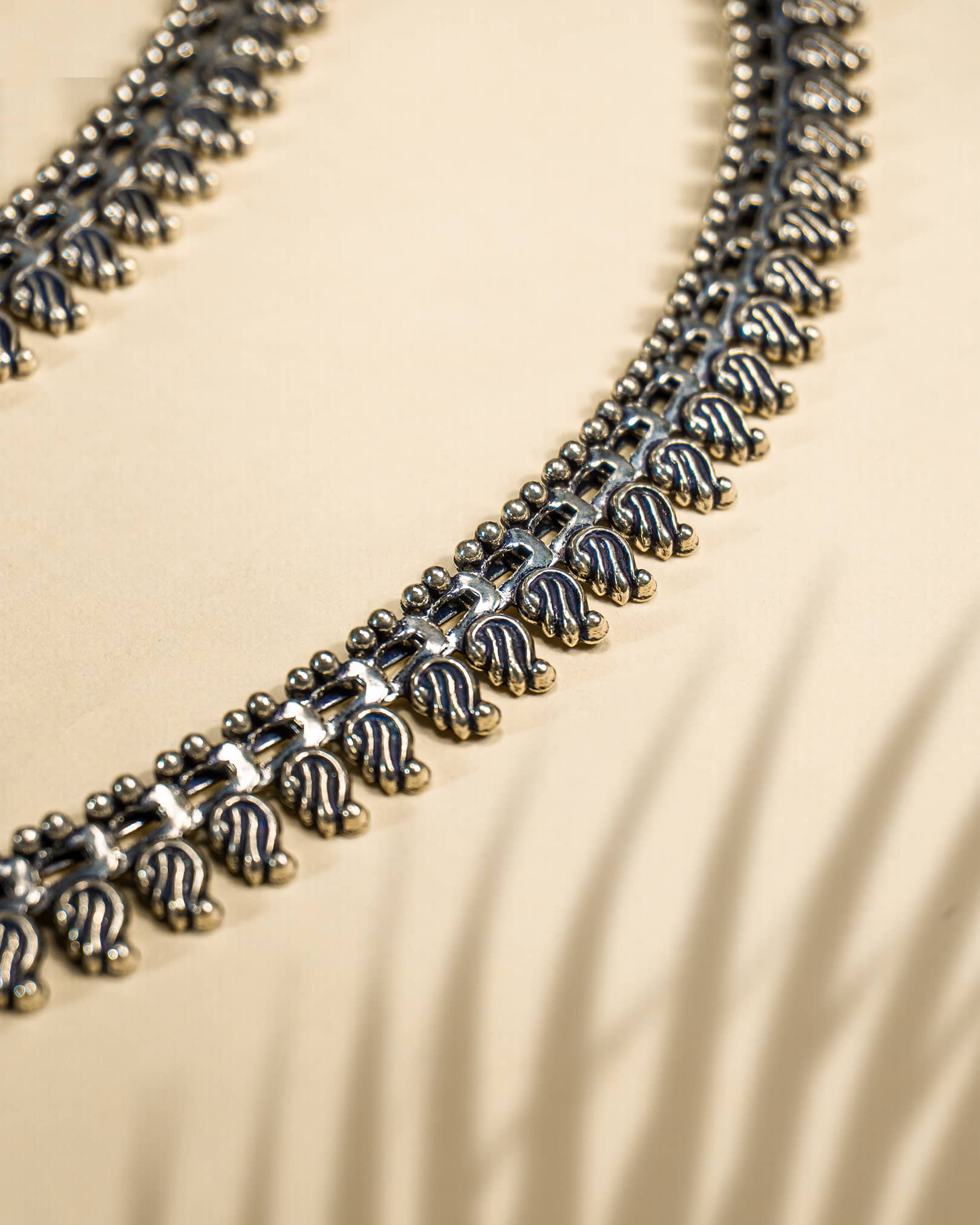 Pair of traditional oxidized silver anklets featuring repeating paisley mango motifs and small silver beads detail