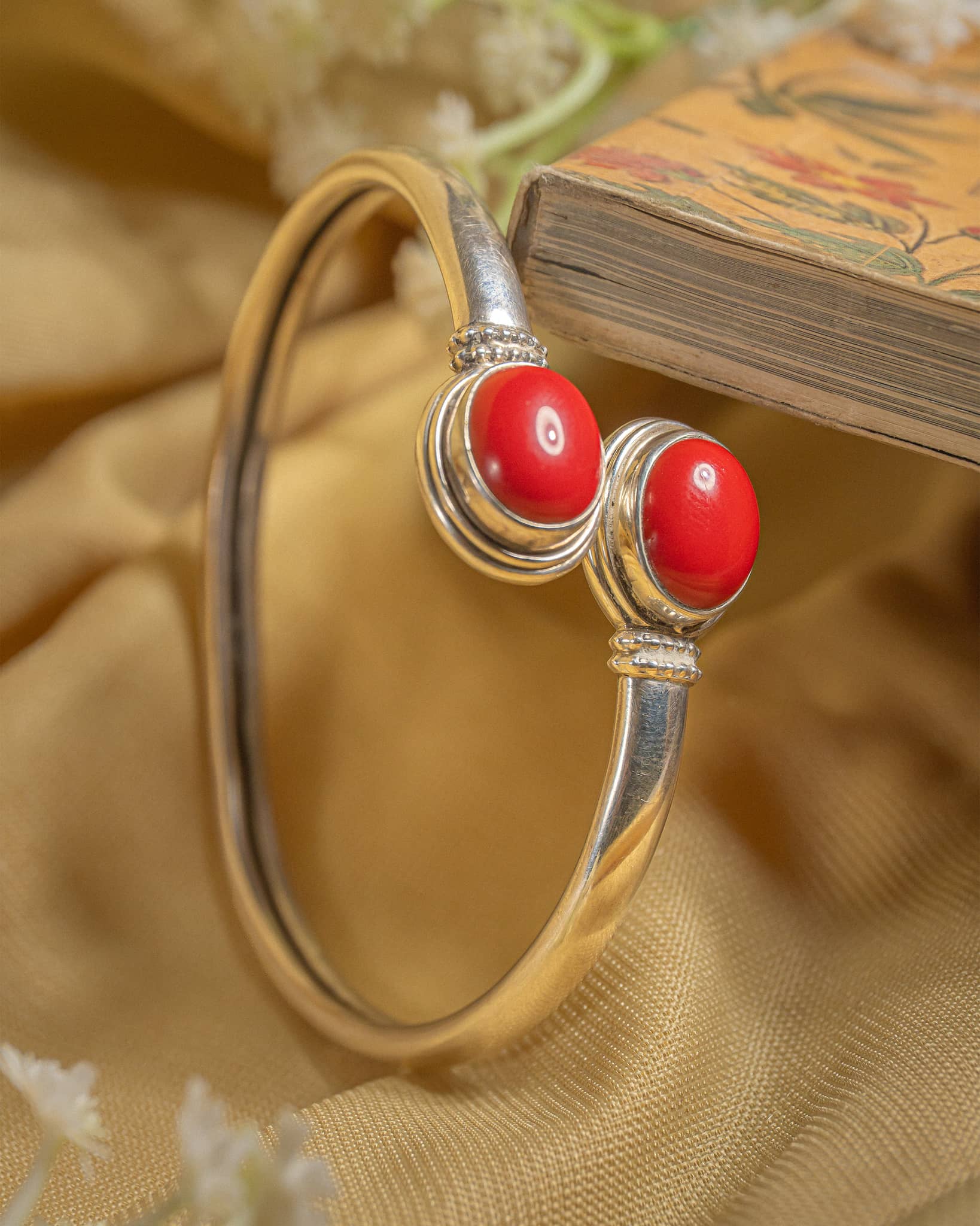 Polished silver open cuff kada featuring round red onyx stones at the ends.