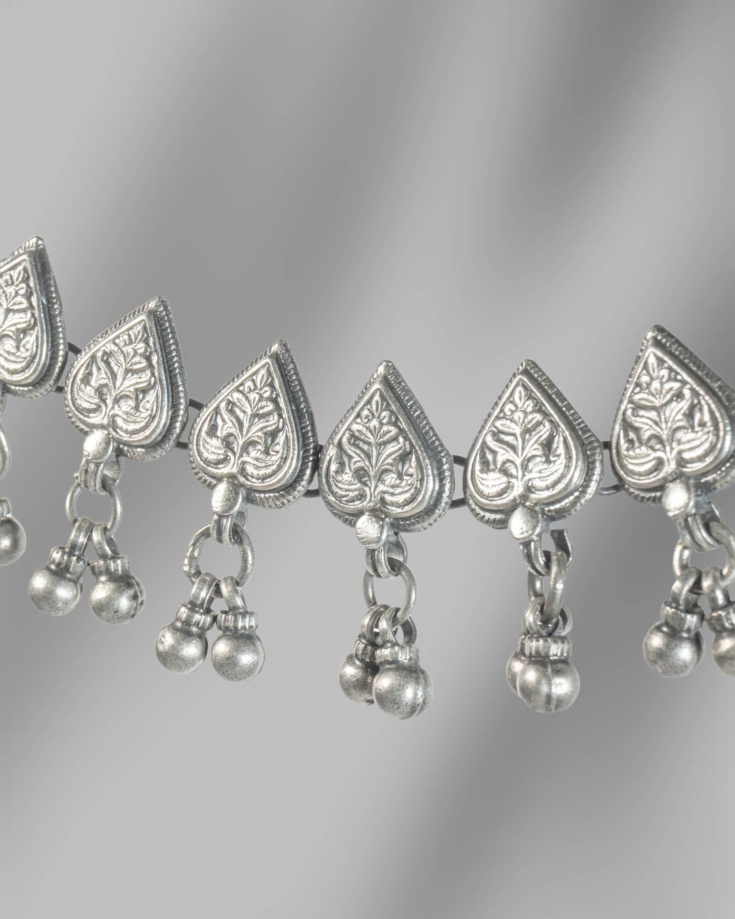 Silver necklace with heart-shaped pendants and hanging beads on a gray background
