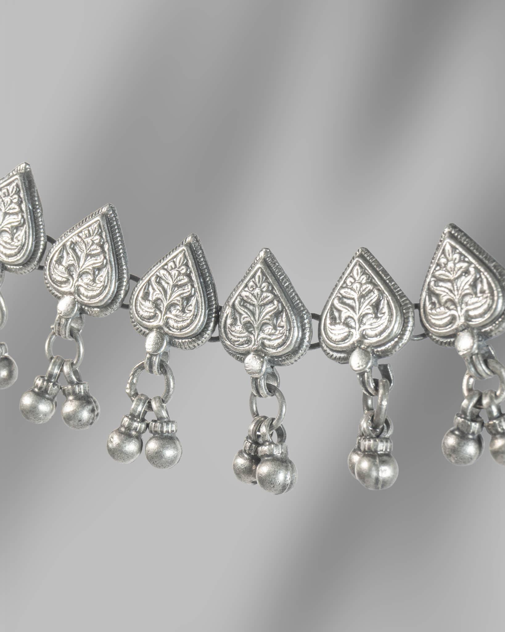 Silver necklace with heart-shaped pendants and hanging beads on a gray background