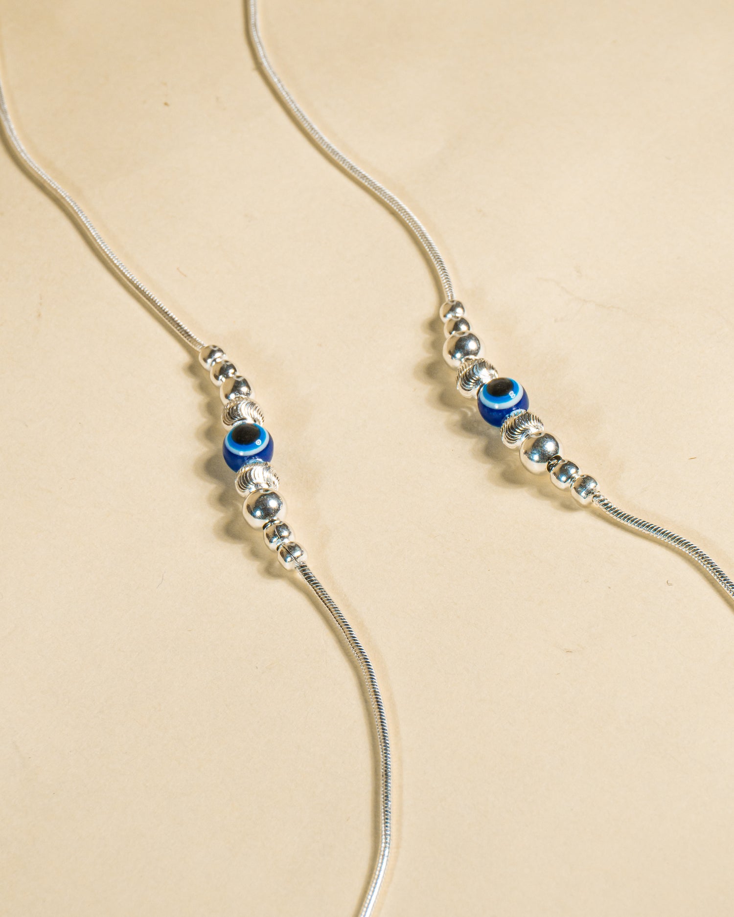 925 Sterling Silver Nazariya Payal featuring a blue evil eye bead on a snake chain, isolated on white background.