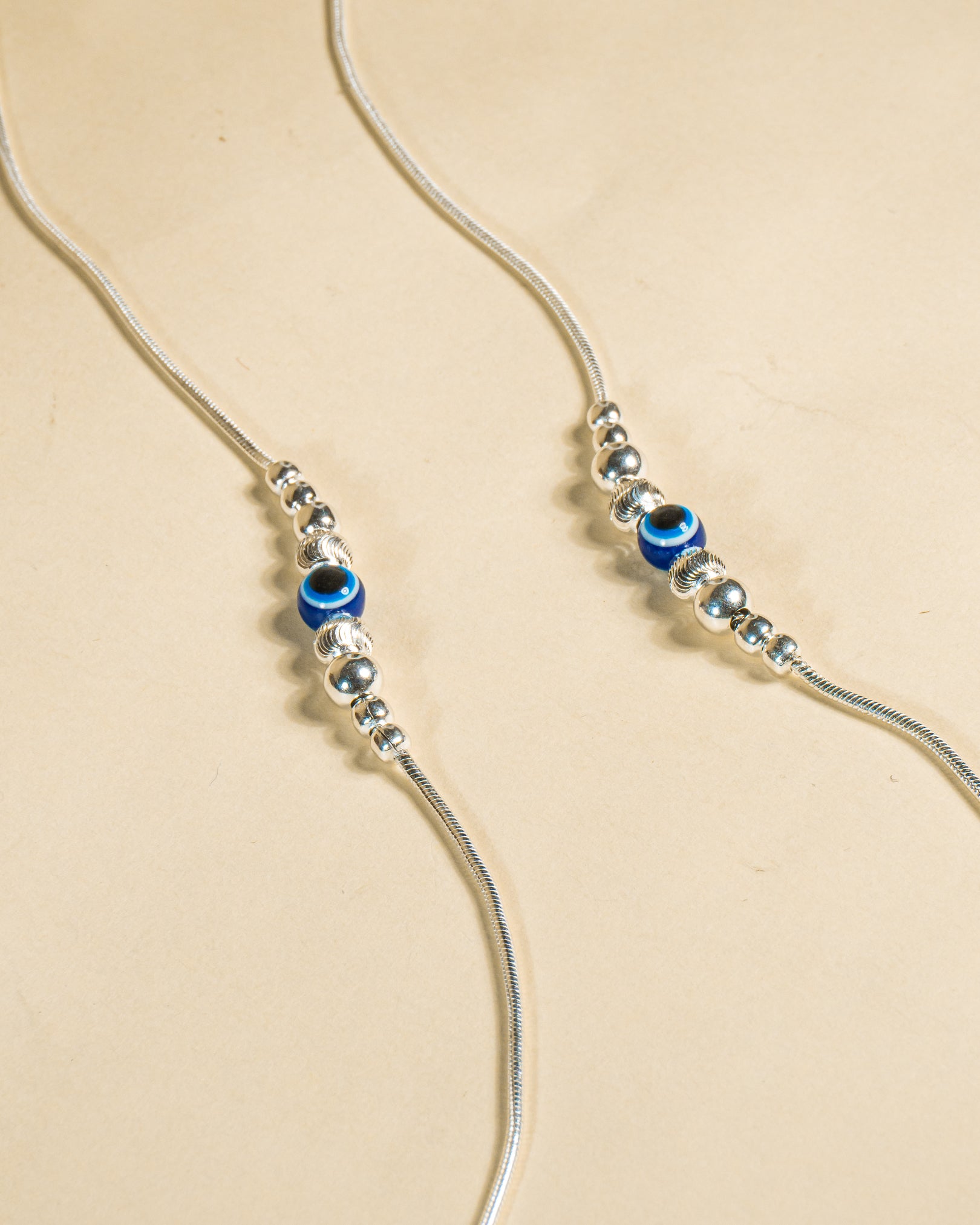 925 Sterling Silver Nazariya Payal featuring a blue evil eye bead on a snake chain, isolated on white background.