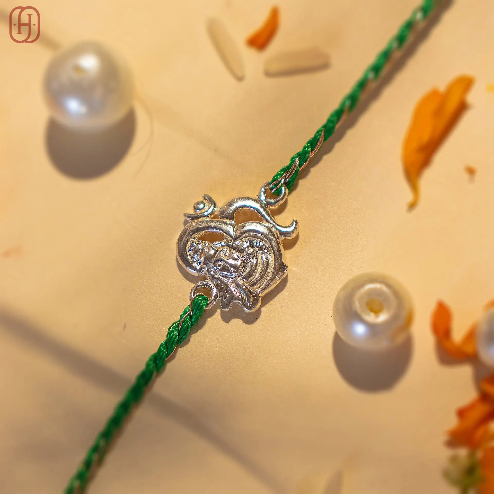 92.5 silver rakhi for brother with a heart-shaped design on a green thread by Hardik Jewels
