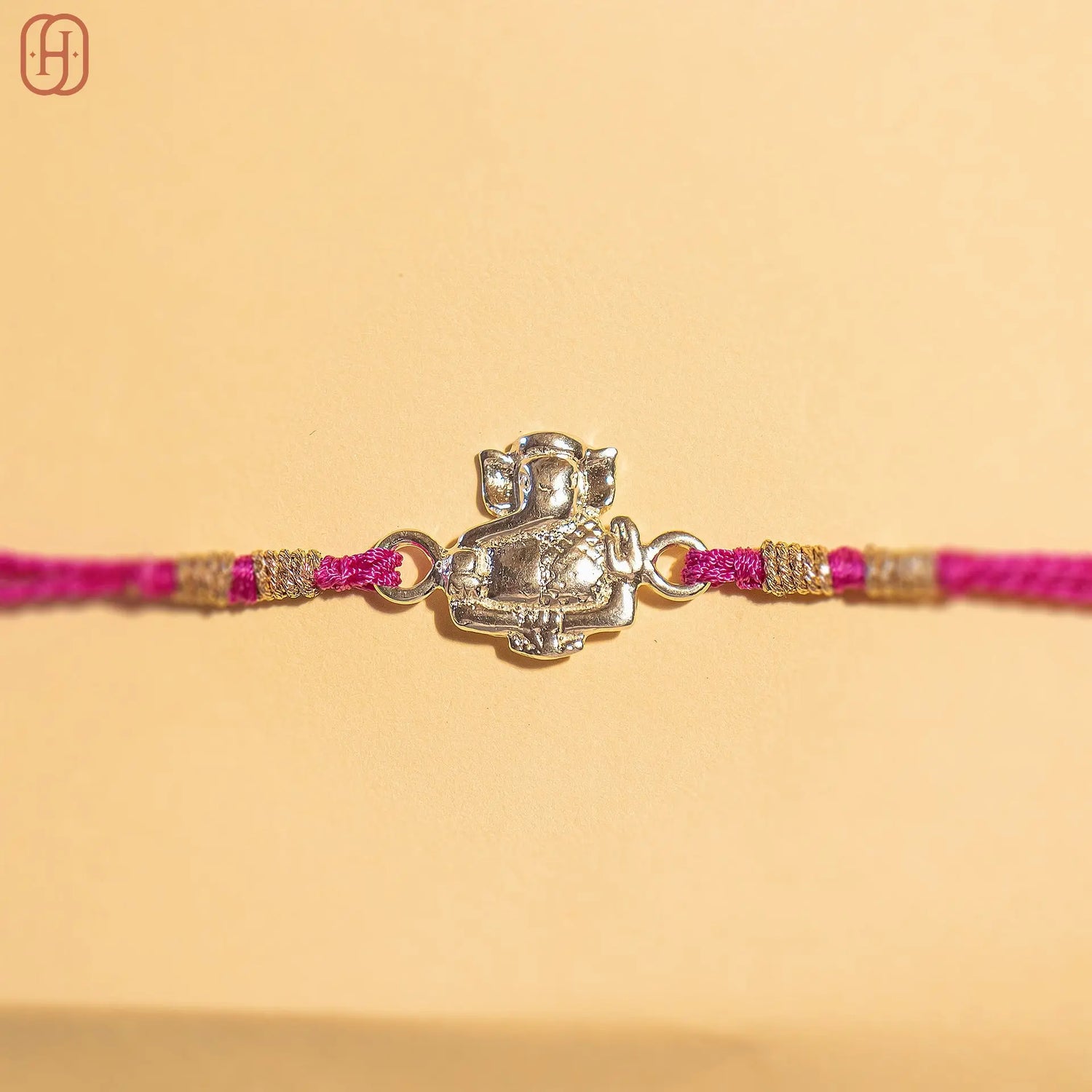 Ganesh Ji face rakhi in silver with pink thread and gold accents from Hardik Jewels