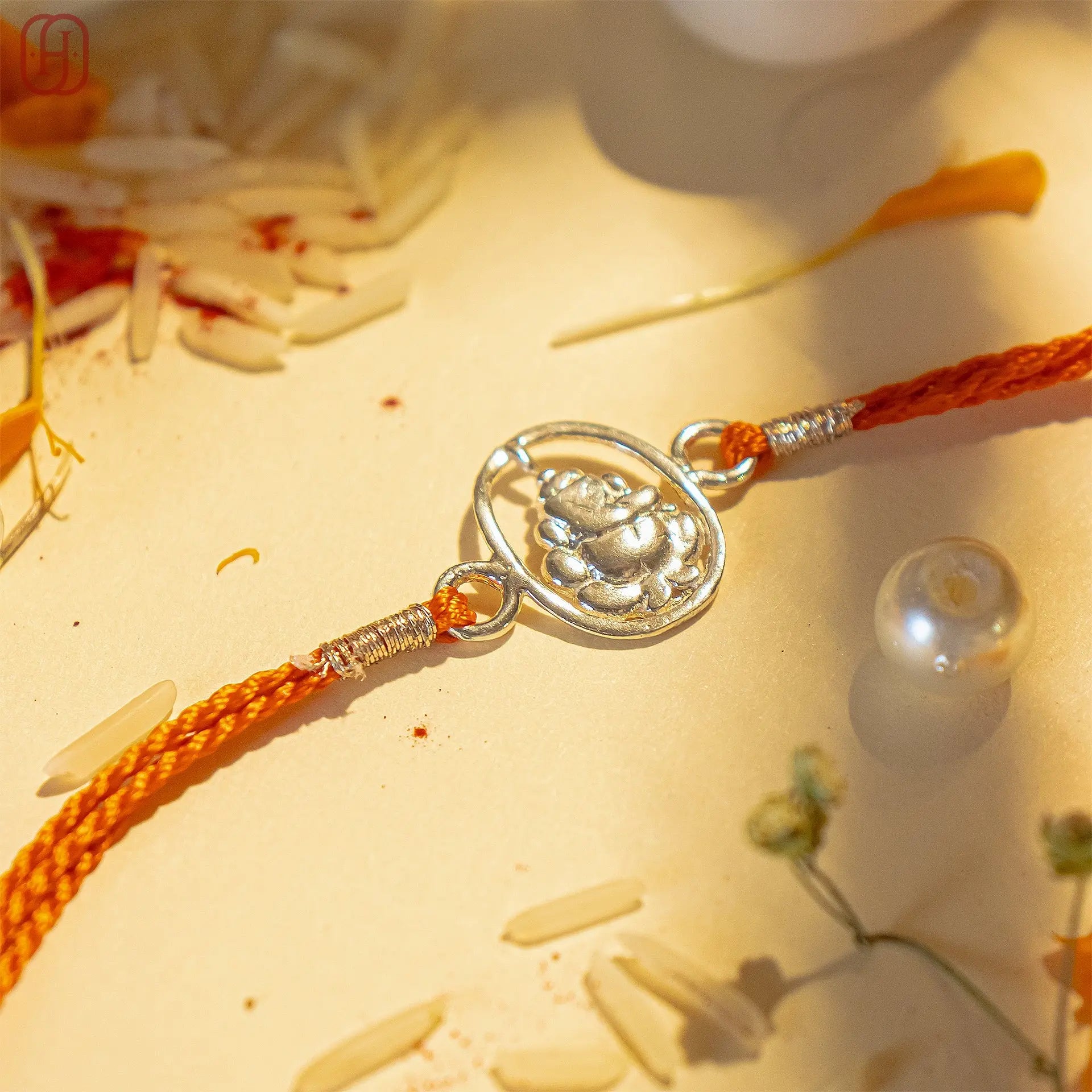 Ganesh Ji silver rakhi with intricate silver Ganesh design on orange braided thread by Hardik Jewels