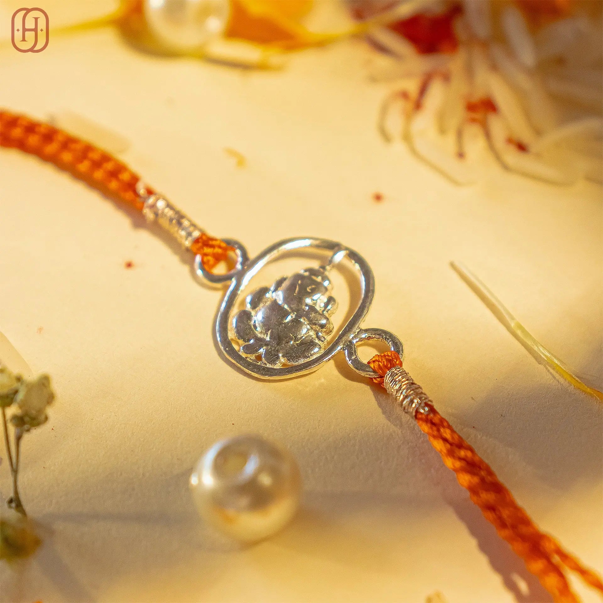 Ganesh Ji silver rakhi with orange thread and intricate silver Ganesh design by Hardik Jewels