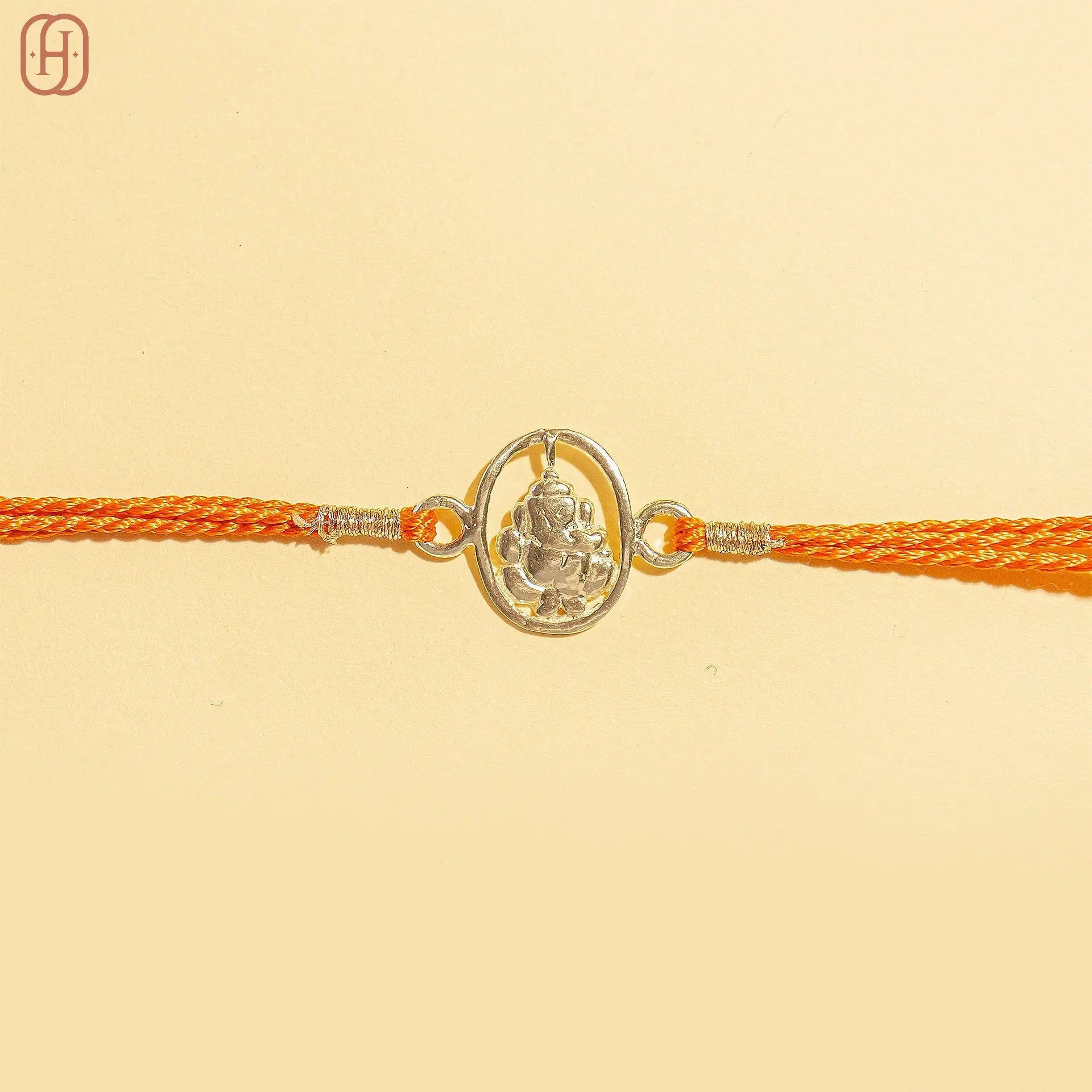 Ganesh Ji silver rakhi with intricate lord Ganesh charm and vibrant orange braided thread