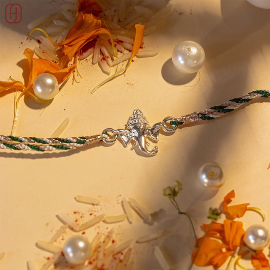 Ganesh silver rakhi with intricate elephant charm and braided green and white thread by Hardik Jewels