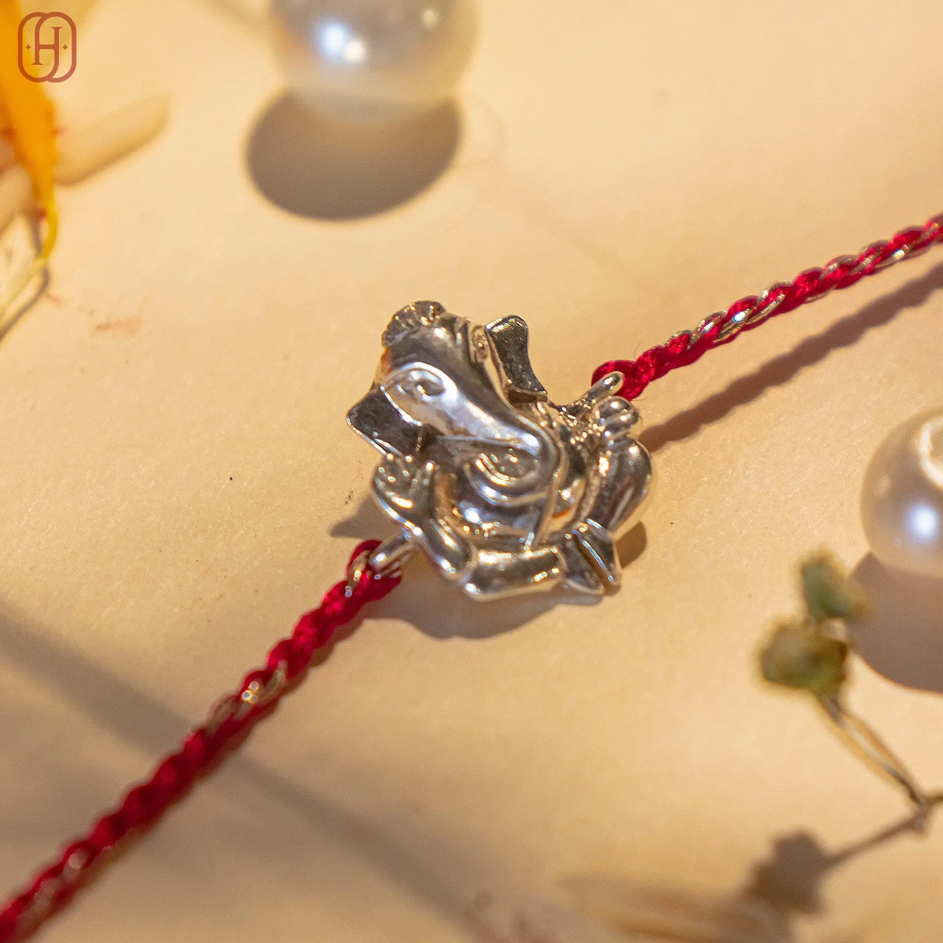 Ganesh silver rakhi with detailed silver Ganesh pendant and red braided thread by Hardik Jewels