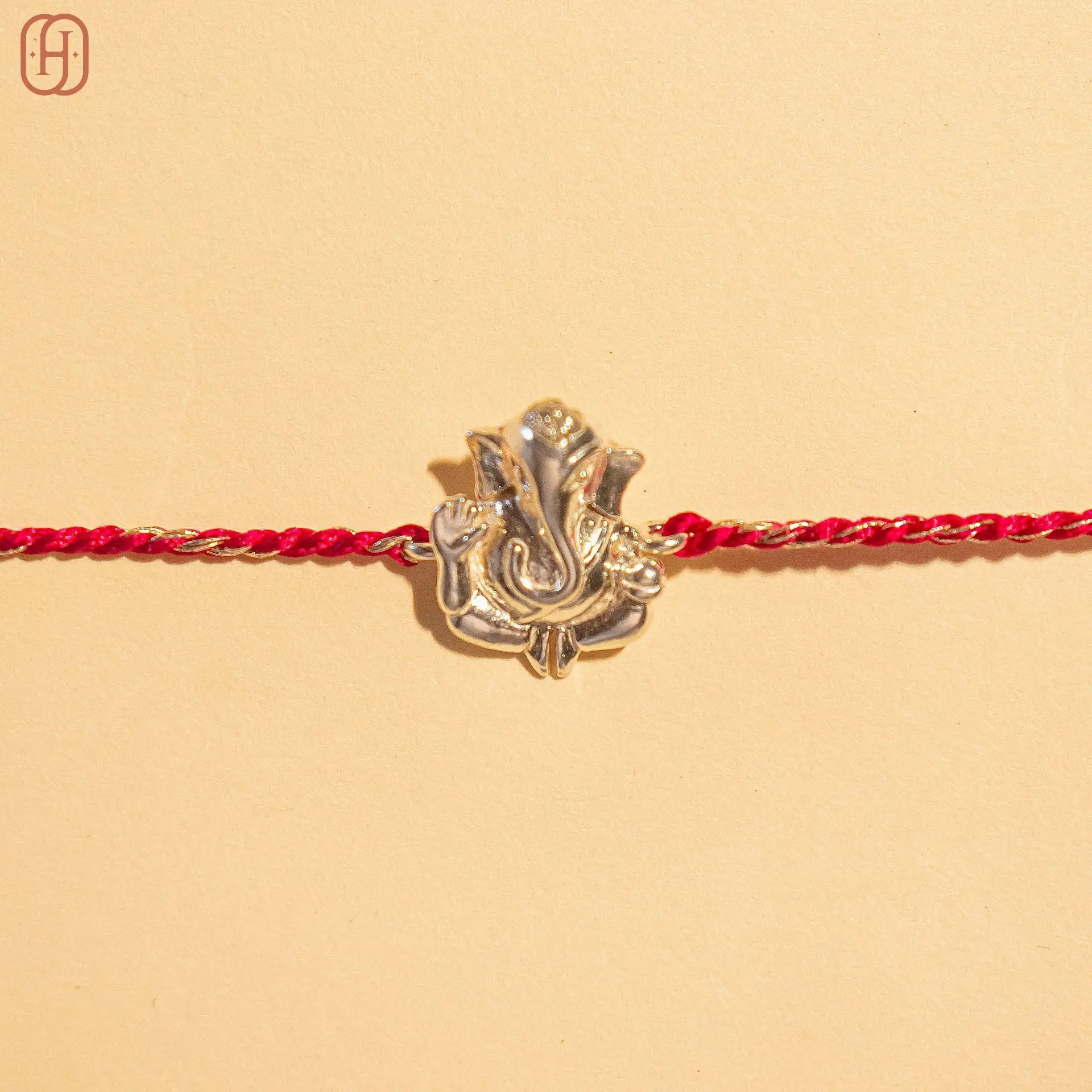 Ganesh silver rakhi with detailed silver Ganesh charm on a red braided thread by Hardik Jewels
