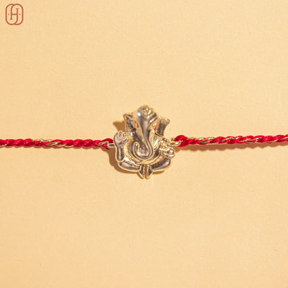 Ganesh silver rakhi with detailed silver Ganesh charm on a red braided thread by Hardik Jewels