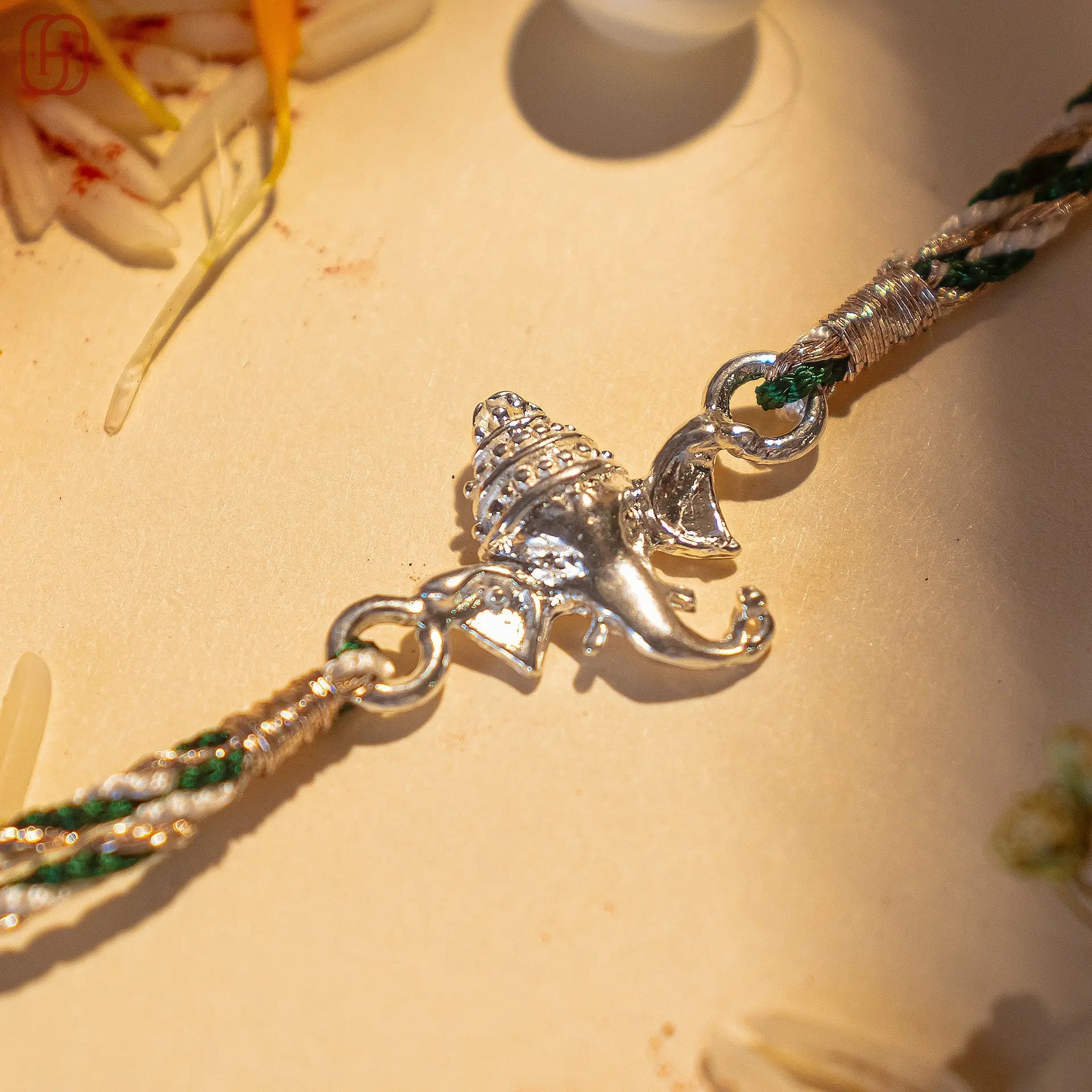 Ganesh silver rakhi with detailed Lord Ganesha charm on a braided green and white thread by Hardik Jewels