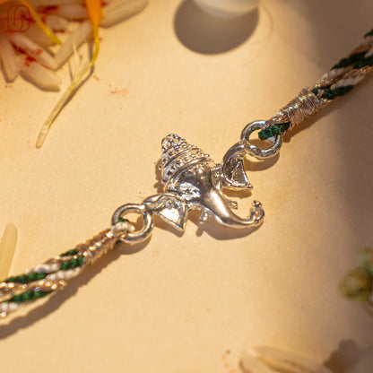 Ganesh silver rakhi with detailed Lord Ganesha charm on a braided green and white thread by Hardik Jewels