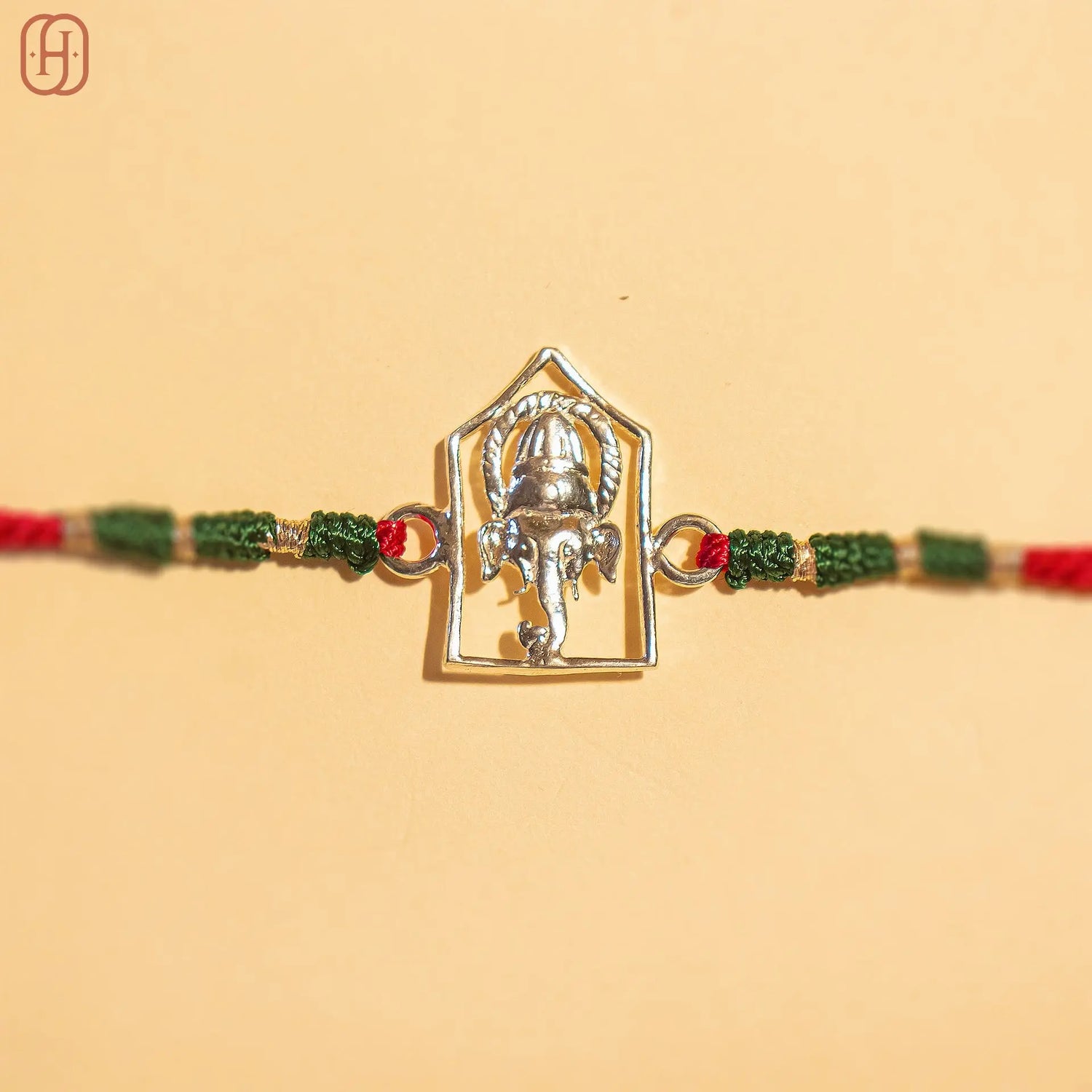 Silver Ganesh Ji face rakhi online with red and green braided thread by Hardik Jewels
