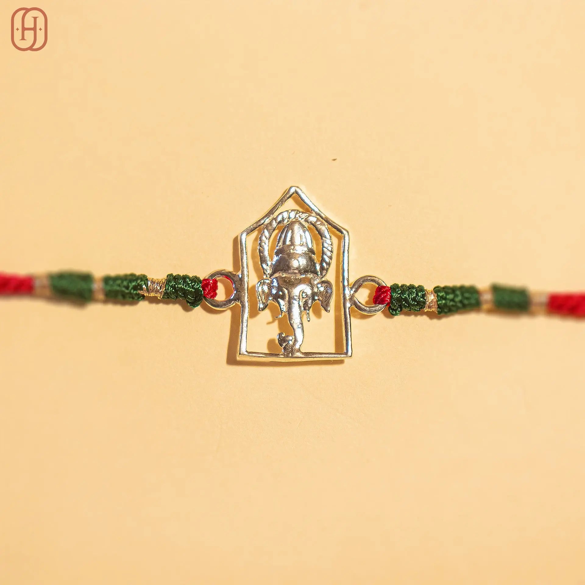 Silver Ganesh Ji face rakhi online with red and green braided thread by Hardik Jewels