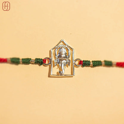 Silver Ganesh Ji face rakhi online with red and green braided thread by Hardik Jewels