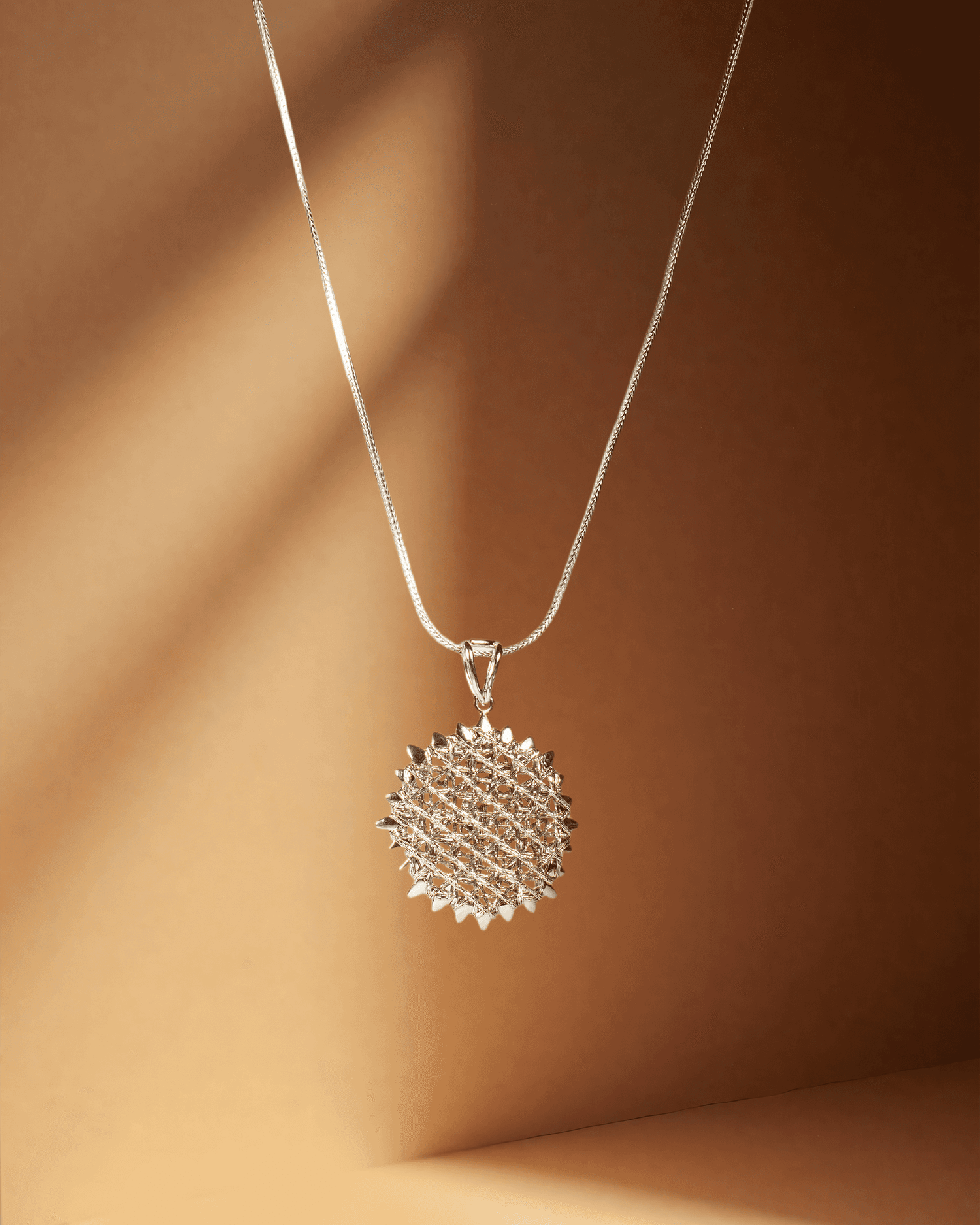 Silver necklace with a textured round pendant on a brown background