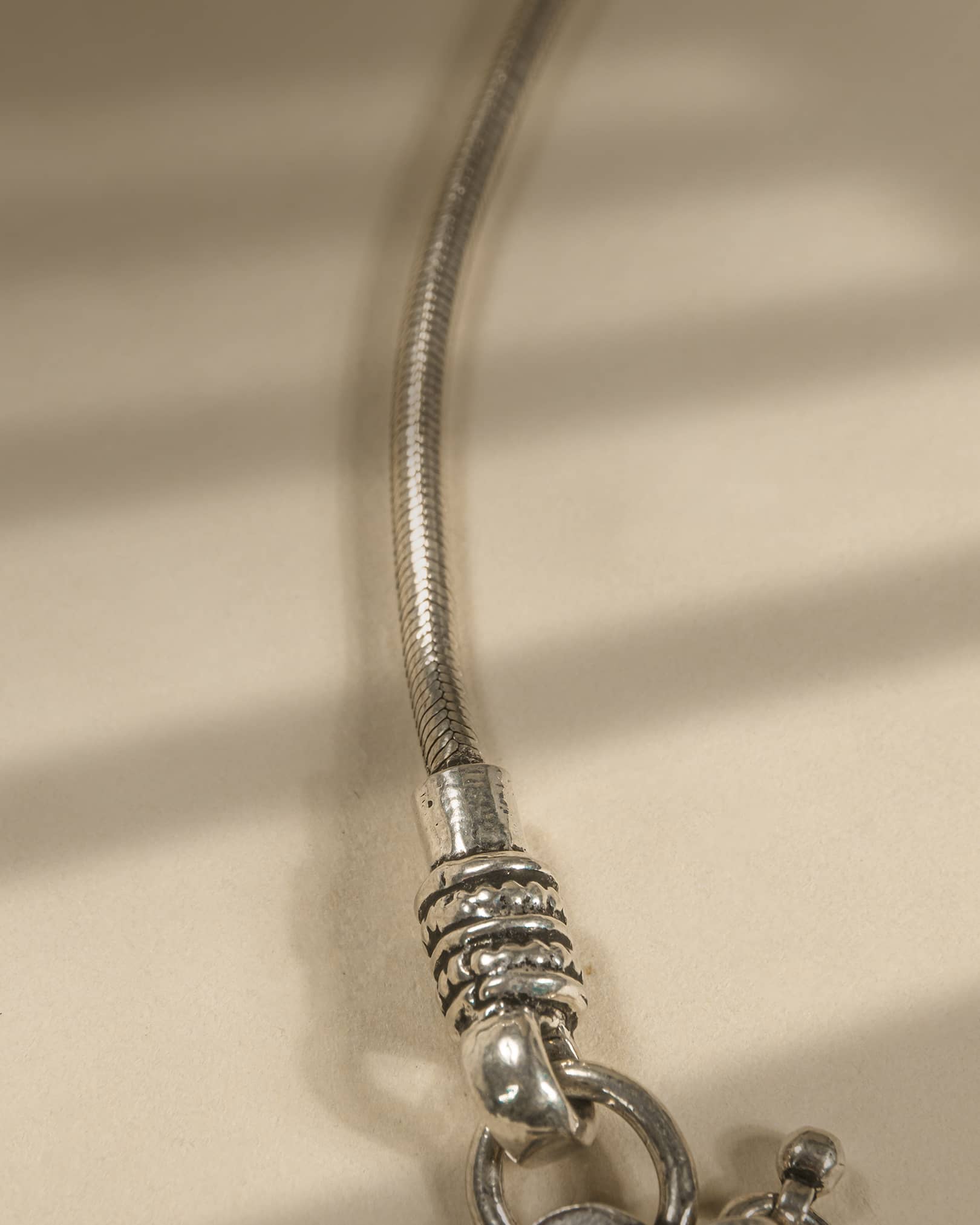 Close-up of a silver bracelet on a beige fabric background