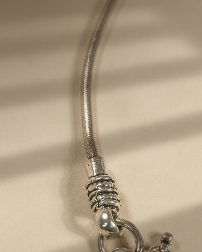 Close-up of a silver bracelet on a beige fabric background