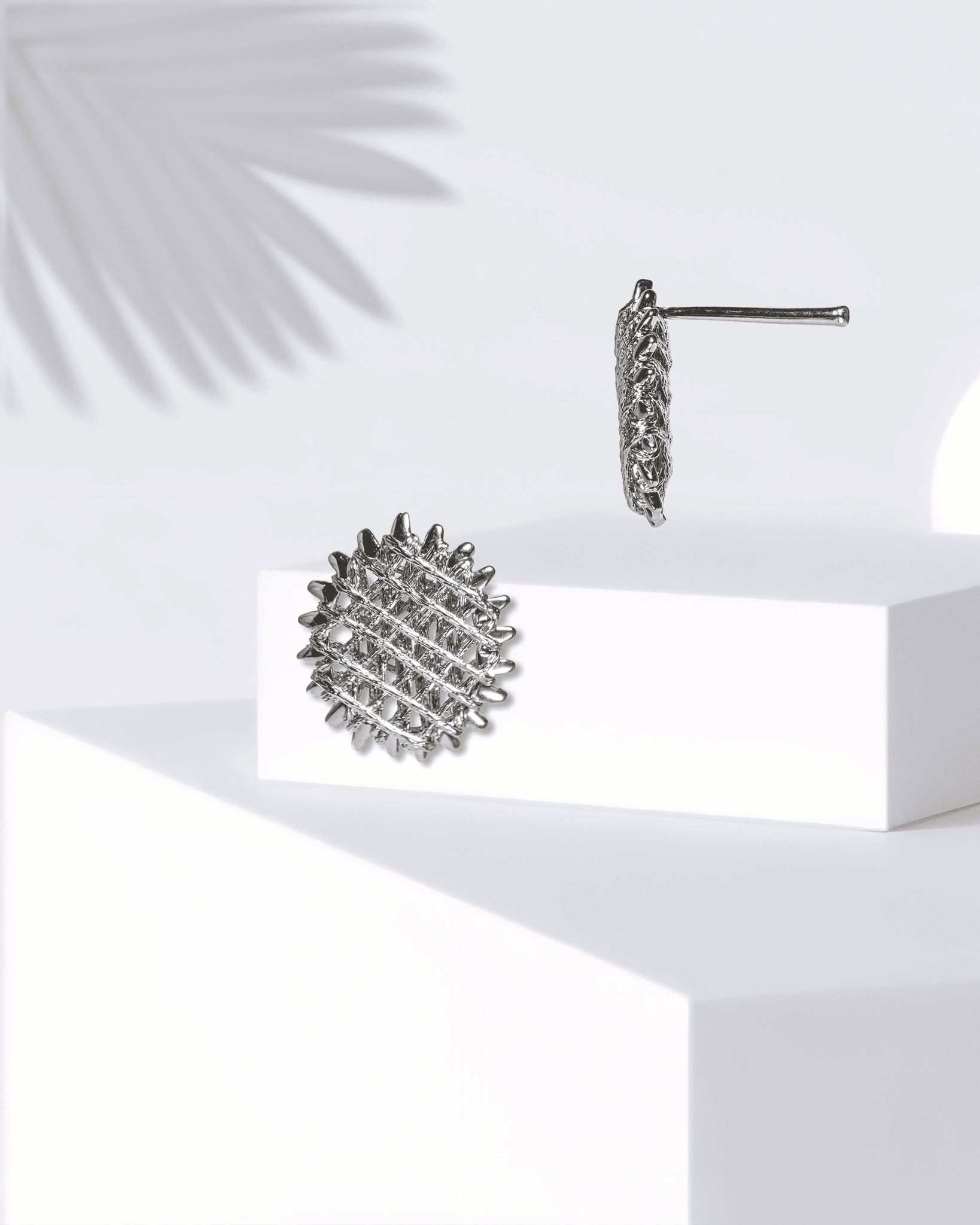 Silver textured earrings on a white surface with a light background