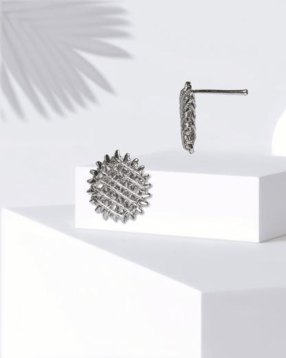 Silver textured earrings on a white surface with a light background