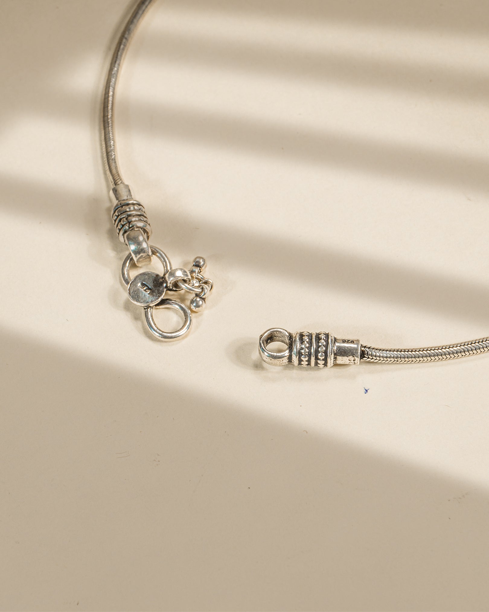 Close-up of a silver bracelet with clasp on a beige fabric background