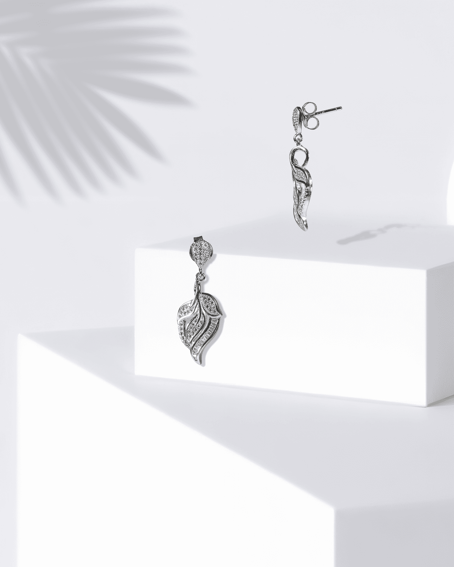 Silver earrings on a white surface with a light background