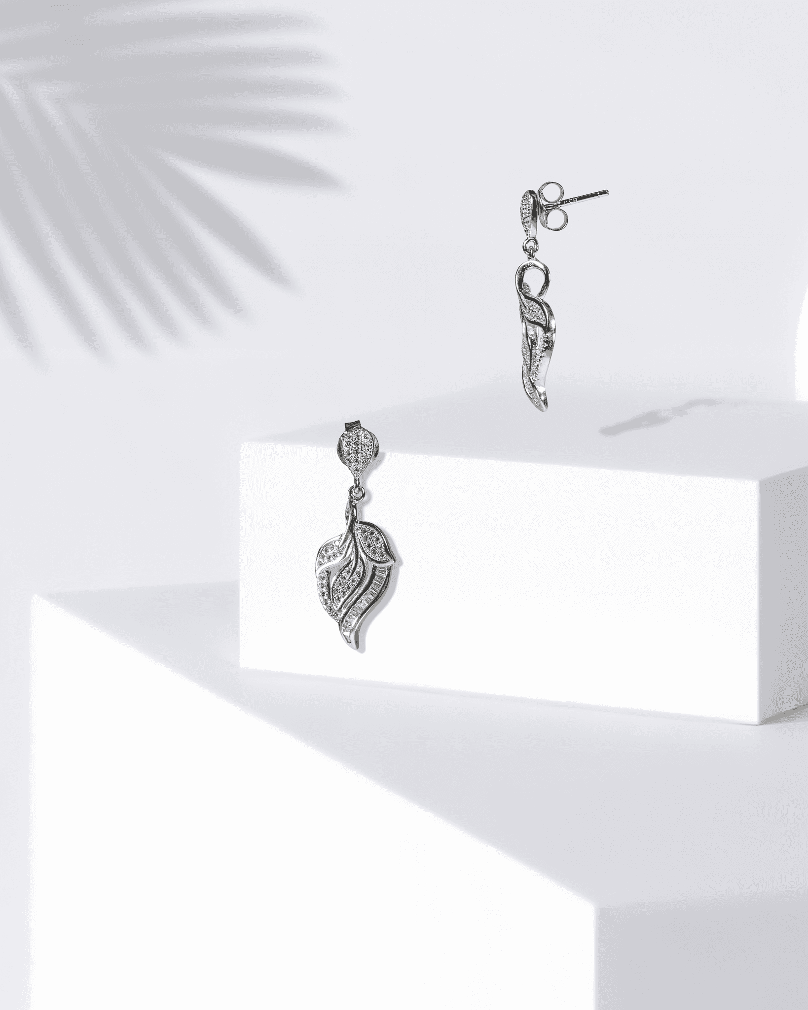 Silver earrings on a white surface with a light background