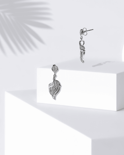Silver earrings on a white surface with a light background