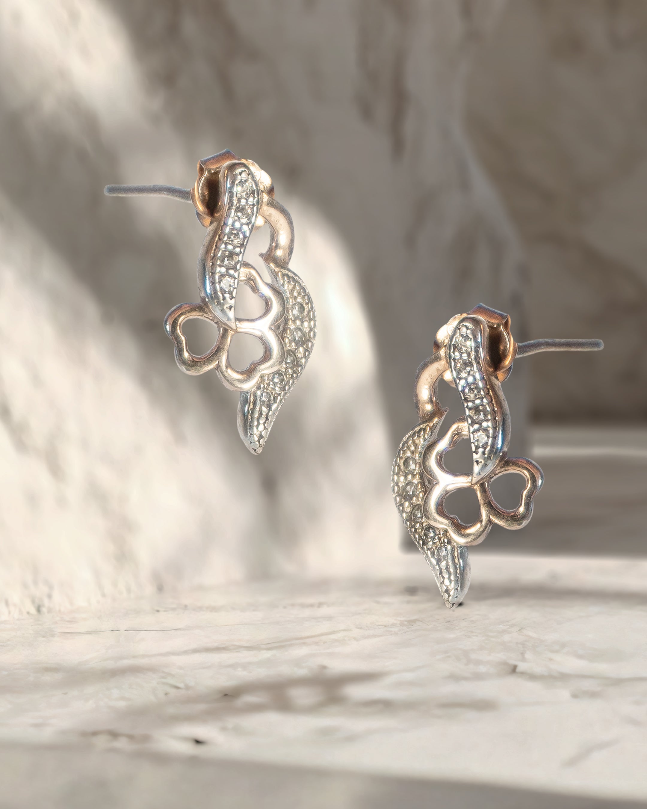 Pair of silver earrings with intricate designs on a marble surface