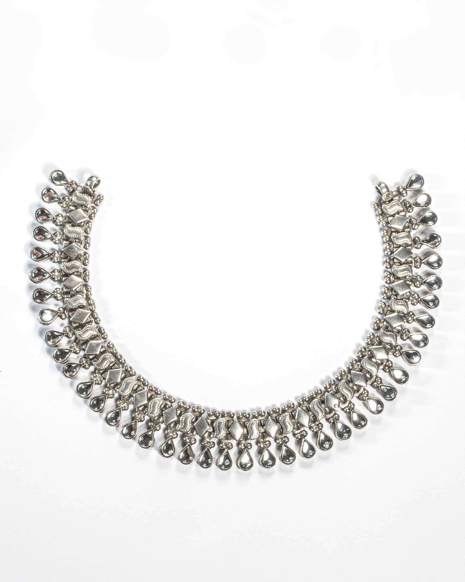 Silver necklace with teardrop-shaped beads on a white background
