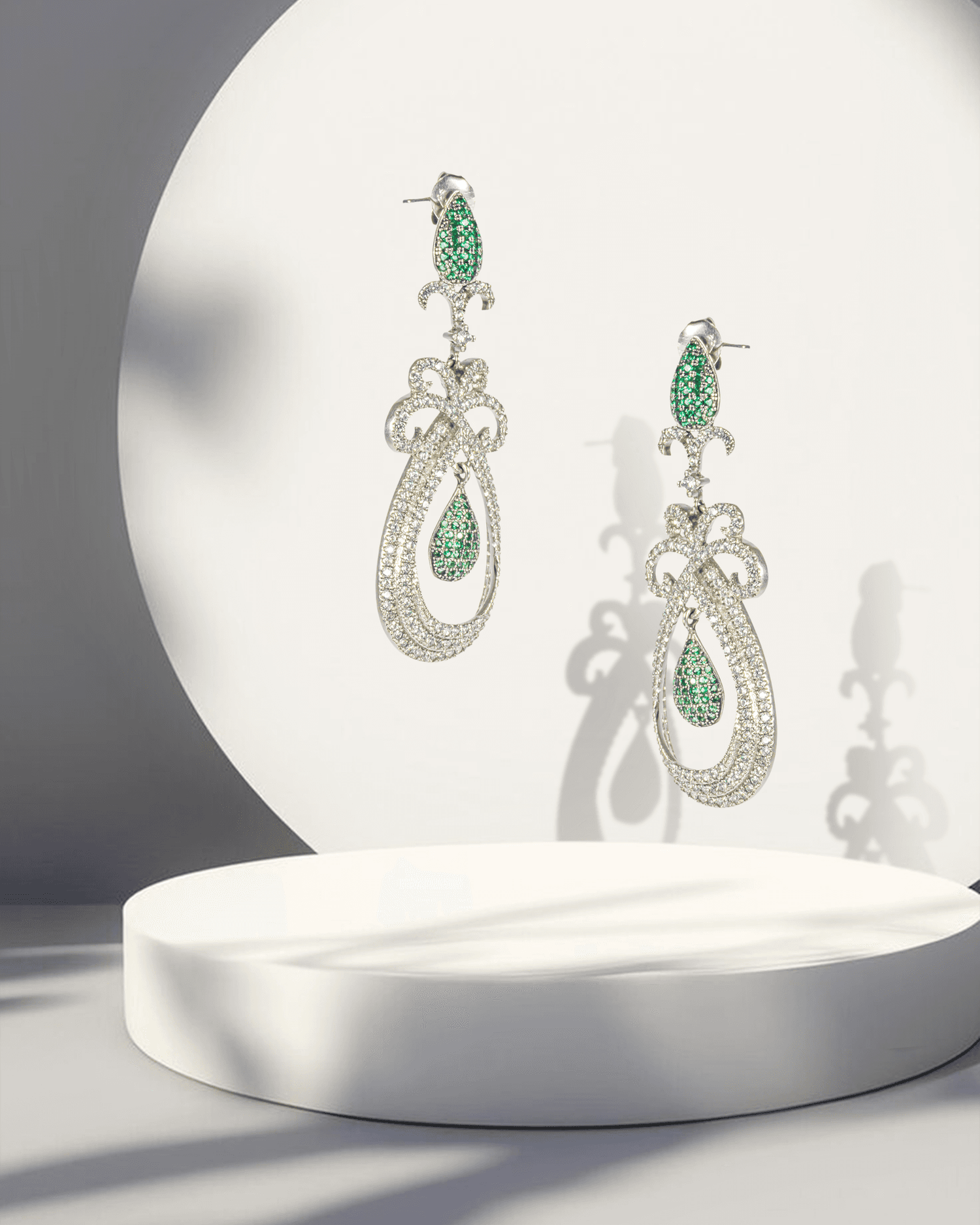 Pair of earrings with green gemstones on a white platform