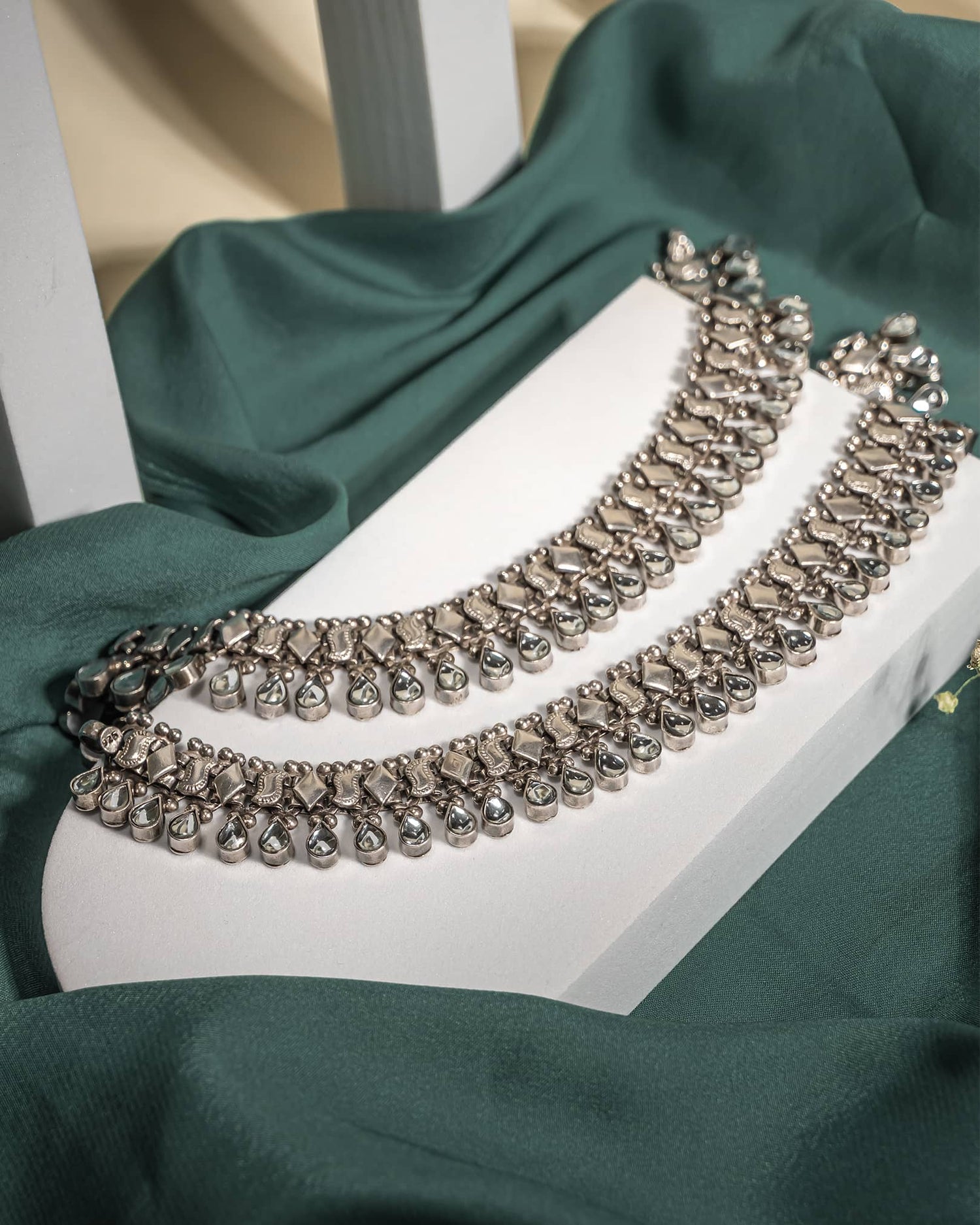 Pair of heavy oxidized 925 sterling silver anklets with hanging teardrop stones displayed on a green fabric background.