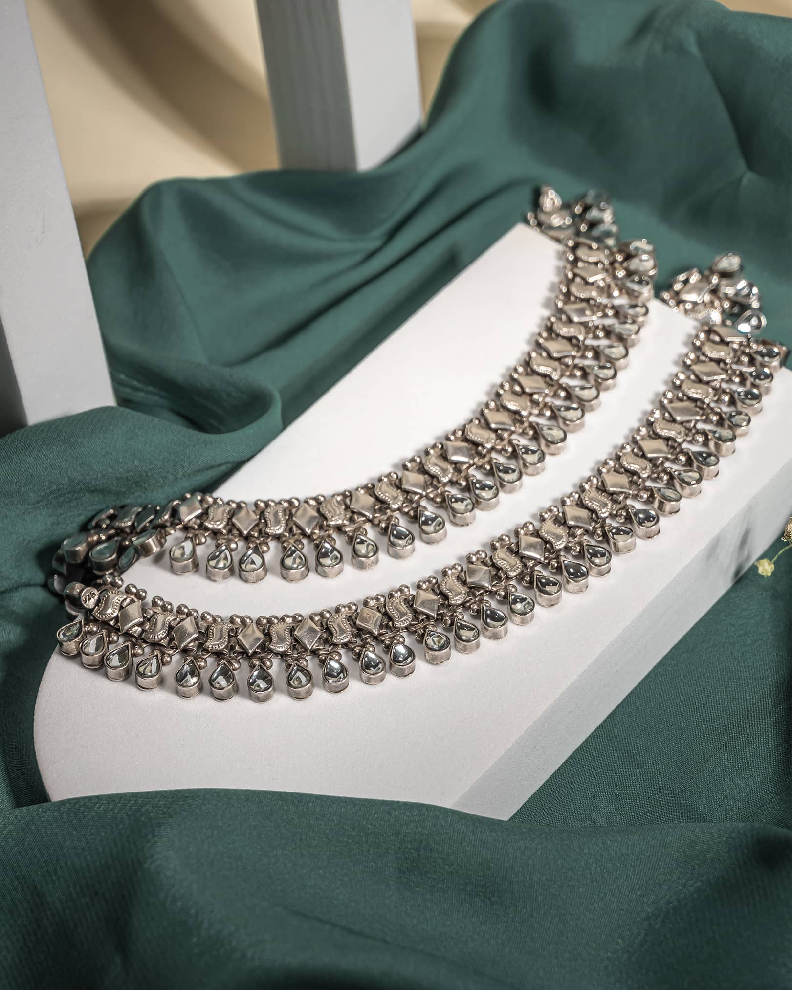 Pair of heavy oxidized 925 sterling silver anklets with hanging teardrop stones displayed on a green fabric background.