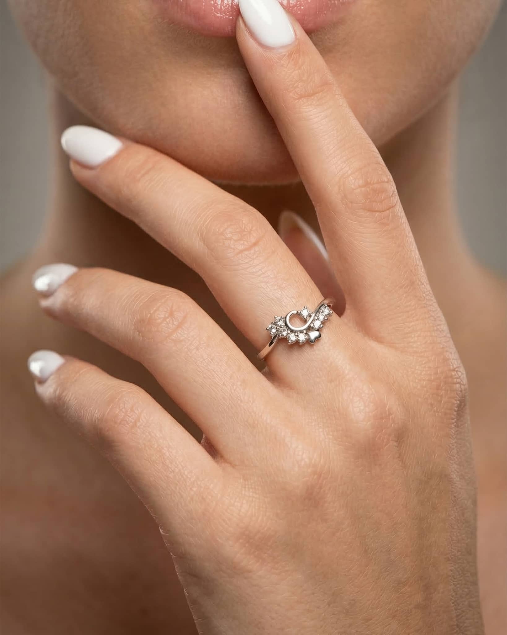 Beautiful woman wearing a dainty 92.5 sterling silver ring featuring a sparkling cz loop and a polished silver heart.