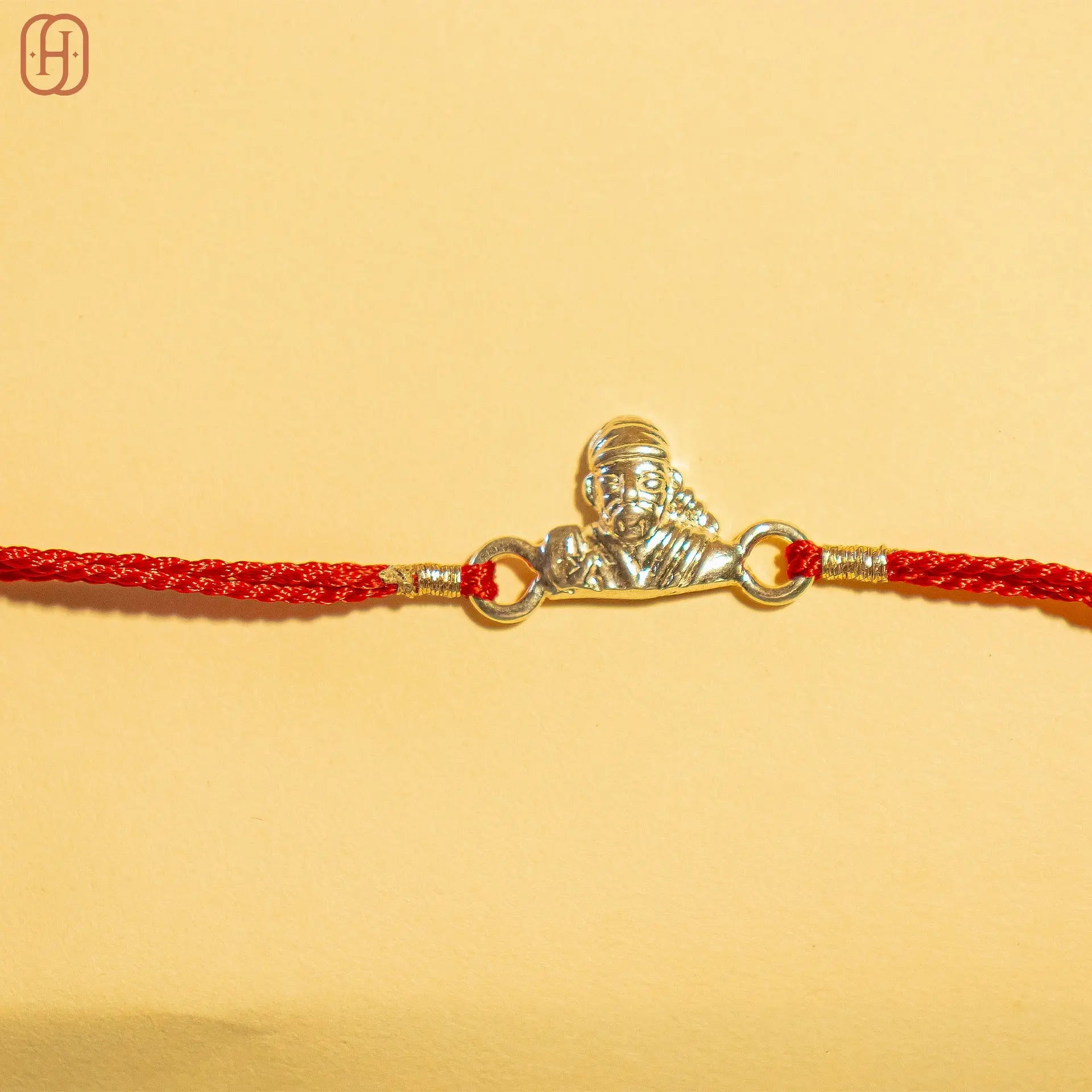 Hardik Jewels 92.5 silver rakhi bracelet with a silver Sai Baba pendant on a red braided thread