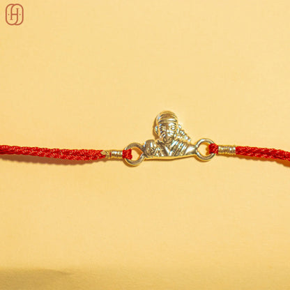 Hardik Jewels 92.5 silver rakhi bracelet with a silver Sai Baba pendant on a red braided thread